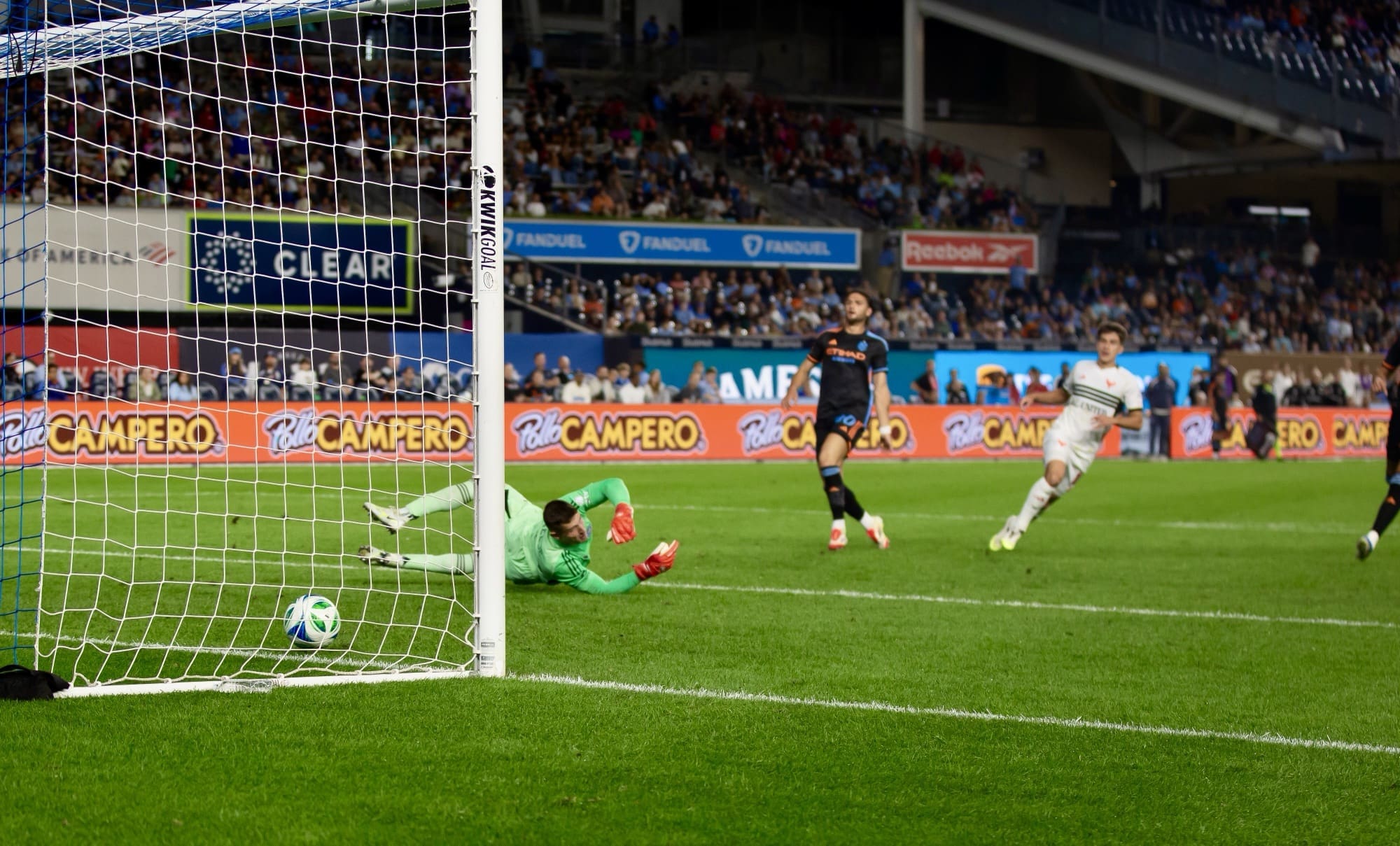 New York City FC goalkeeper Matt Freese diving in vain as DC United midfielder Gabriel Pirani scores, with NYCFC defender Justin Haak nearby during MLS match at Yankee Stadium
