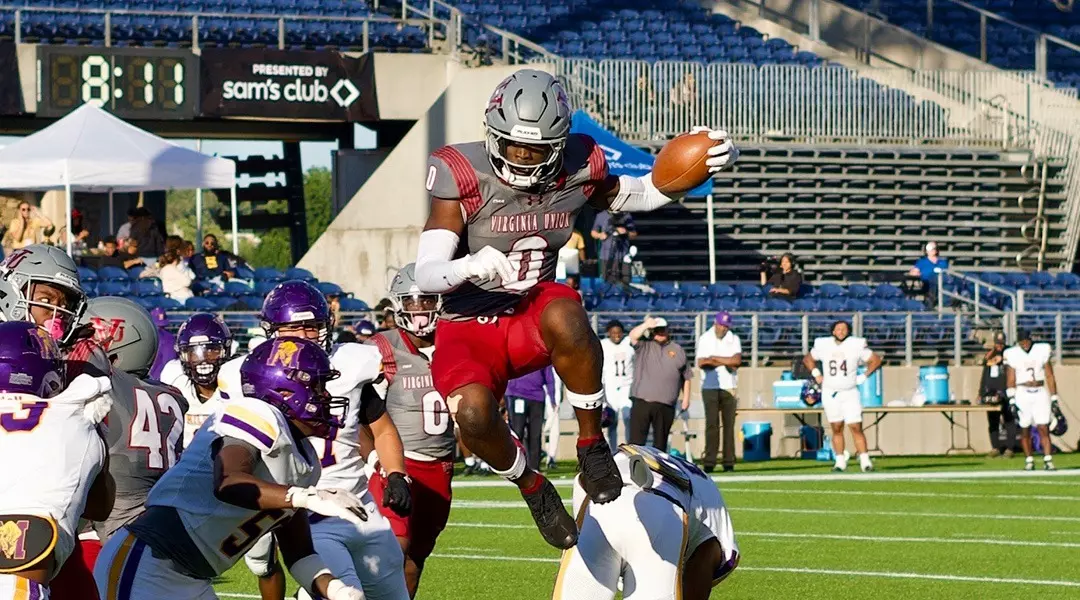 Virginia Union University football player Curtis Allen hurdles over defender during game action