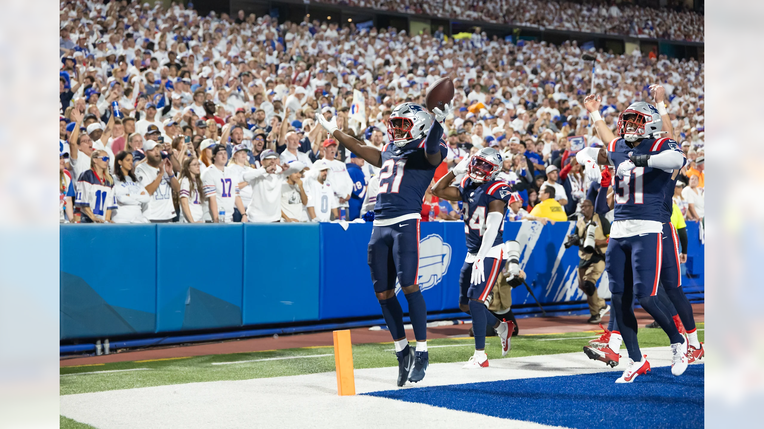 New England Patriots safety Jaylinn Hawkins leaps in celebration after a crucial turnover, surrounded by teammates in Highmark Stadium's end zone during Week 5 victory against the Buffalo Bills