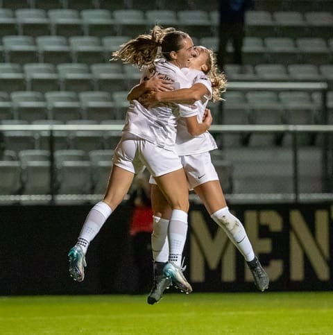 Army West Point's Bella Conti and Brigid Duffy leap into mid-air embrace celebrating goal against Loyola at Clinton Field on October 24, 2025