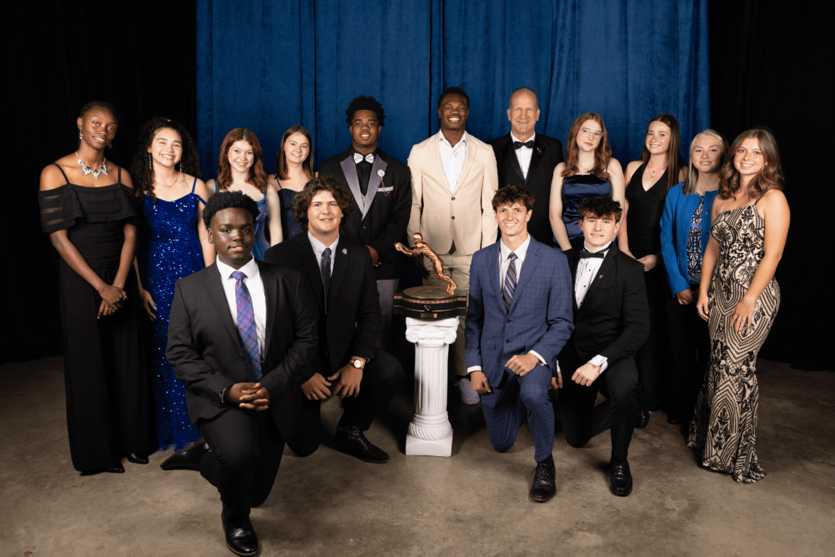 2025 Biletnikoff Award scholarship recipients pose for a group photo in formal attire with the Biletnikoff Trophy at center. Mandatory Credit: Biletnikoff Award.