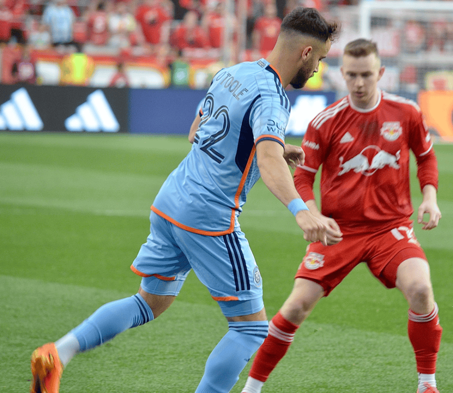 Photo Credit Soccer LI Magazine New York City Defender Kevin O'Toole takes on New York Red Bulls Cam Harper one on one.