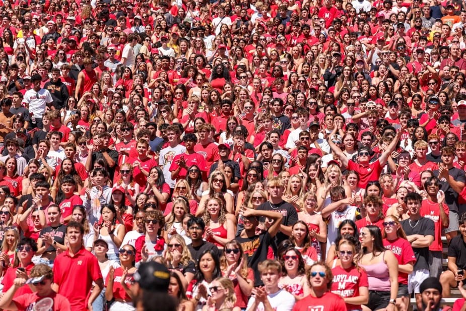 Packed Maryland Terrapins football stadium crowd, filled with fans wearing predominantly red and white shirts, cheering enthusiastically during the game against Florida Atlantic