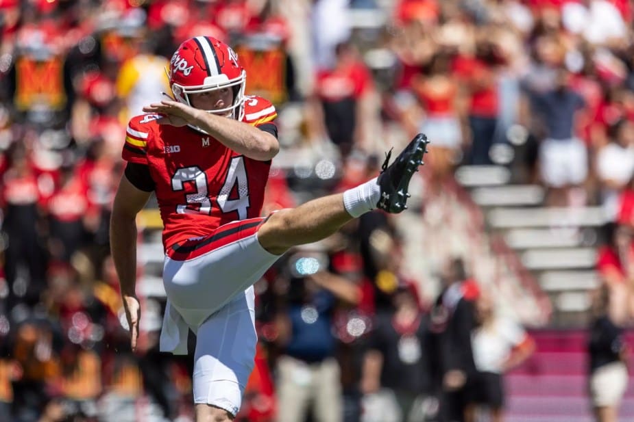 Maryland punter #34 Bryce McFerson kicks the football during a game, wearing the team's red jersey with white pants