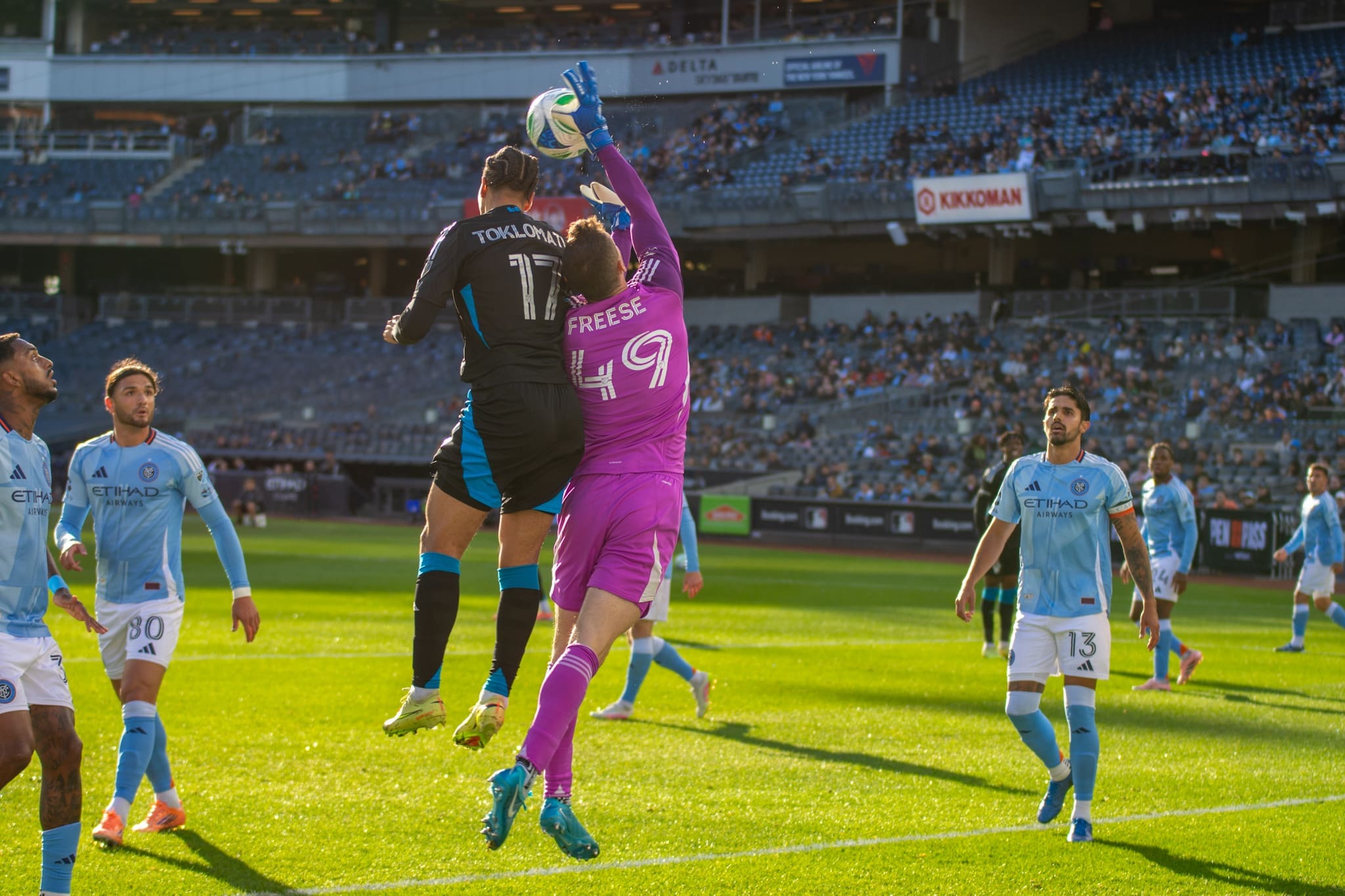New York City FC goalkeeper Matt Freese number 49 in pink jersey leaps to catch ball above Charlotte FC forward Idan Toklomati number 11 in black jersey during MLS Cup Playoffs Game 1 at Yankee Stadium in regulation play keeping score 0-0