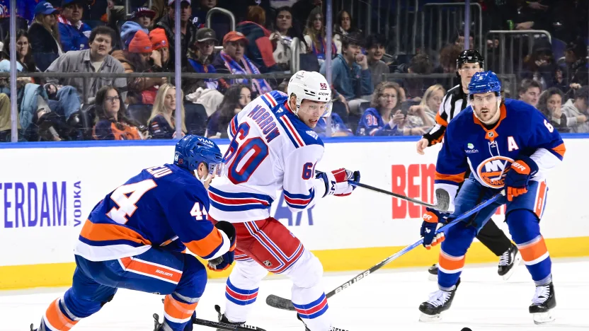 12/27/2025 UBS Arena, Elmont, NY., Scott Morrow plays the puck against two Islanders players. Mandatory Credit: New York Rangers