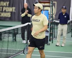 An Army West Point men’s tennis player walks near the net during a match at the West Point indoor tennis center.