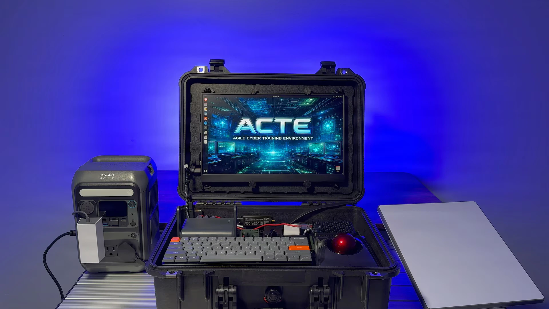 Senior Master Sgt. Taylor Gow stands beside a portable cyber training case with a screen and keyboard setup.